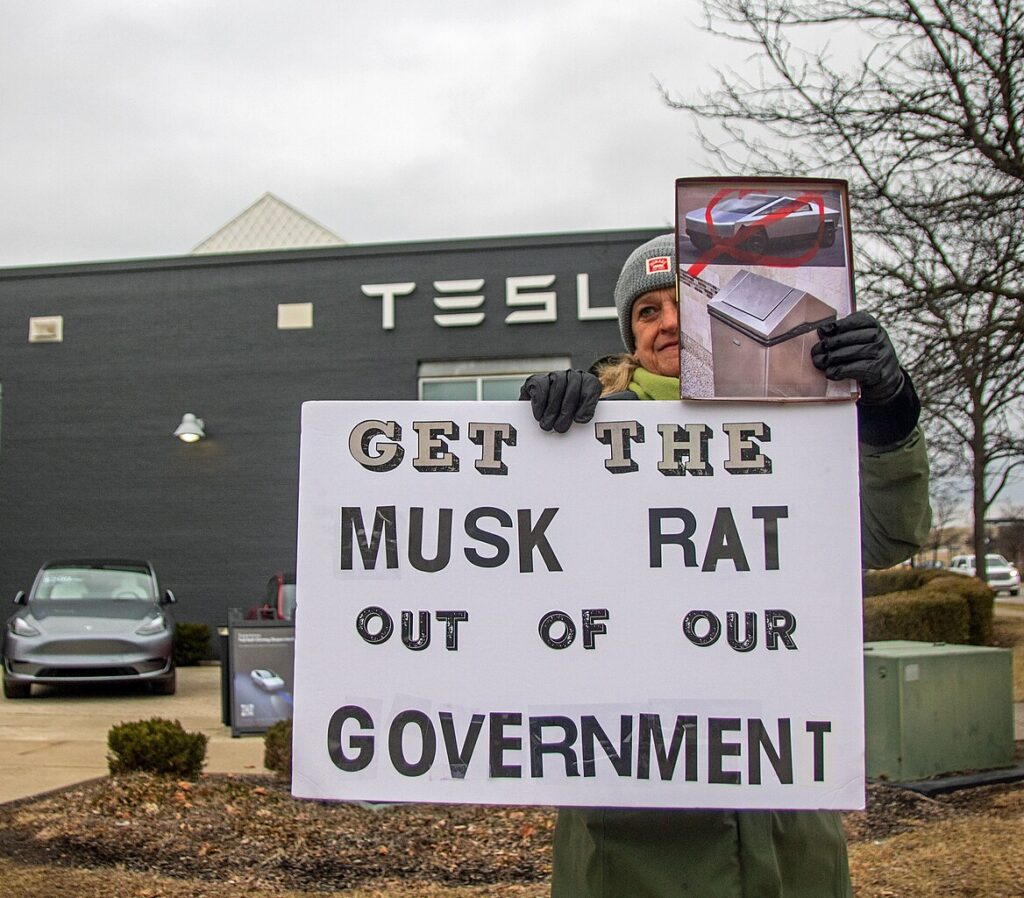 Tesla protest kvinna med Elon Musk skylt